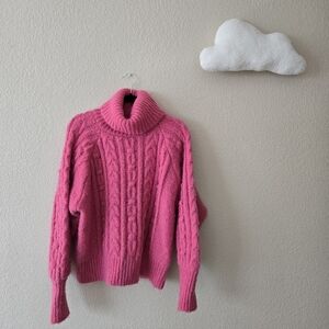 Bold and cozy, this bright pink cable-knit turtleneck sweater brings warmth and